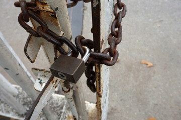 Old lock and rusty lock chain hangs on a old metal gate