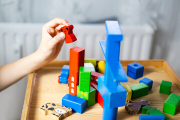 smart child, schoolboy playing with educational toy, wooden geometric figures, blocks in boy's...