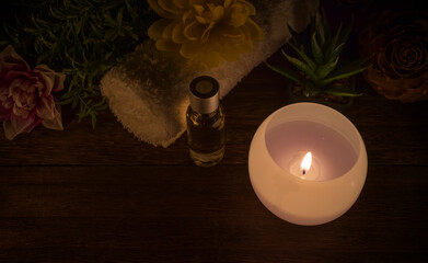 Round candle burning in the dark. Background with lit candle and decorative objects on a wooden base