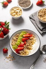 Granola with yogurt, fresh strawberries, kiwi, banana and nuts, seeds. Healthy breakfast. 