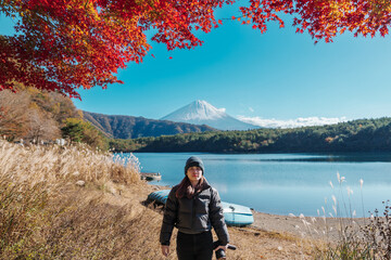 Woman tourist with Fuji Mountain at Lake Saiko in Autumn season, happy Traveler travel Mount Fuji, Yamanashi, Japan. Landmark for tourists attraction. Japan Travel, Destination and Vacation