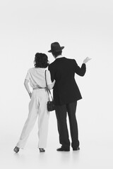 Man and woman in retro-style elegant costumes standing and looking somewhere with attention isolated on white background. Black and white. Concept of retro and vintage, fashion, romance, relationship