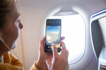 woman taking photos through plane window