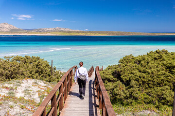 The girl descends onto a paradise beach via a wooden pier.