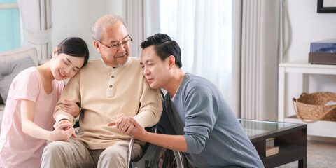Happy elder Asian man using wheelchair while exercise indoor house with his son taking care of him at the retirement age with copy space