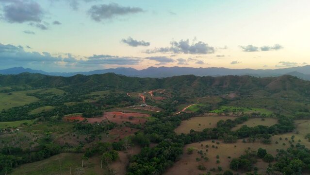 Aerial panorama of green valley at sunset with mountain range layers in the horizon. Beautiful landscape of the Dominican Republic