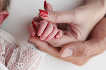 Close-up little hand of child and palm of mother and father. The newborn baby has a firm grip on...