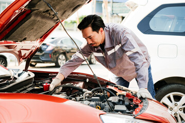 Diversity mechanic teamwork, a Japanese engineer wearing blue uniforms. A man inspects problems of the car engine inside opened car hood. Automobile repairing service. Vehicle maintenance. Labor work - 787280276