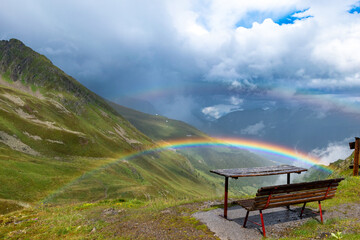 A Bench Embraced by Mountain Majesty and Rainbow Wonder