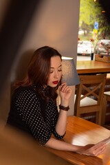 Beautiful woman enjoying a good book at a cozy cafe table with elegant decor and warm lighting