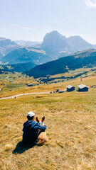 Fototapeta na wymiar Teen boy hugging his girlfriend corgi dog in the Dolomites mountains on a sunny day