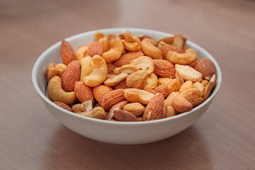 Almond nuts and cashews in a bowl on the table, snacks for beer, nuts in a bowl, close-up