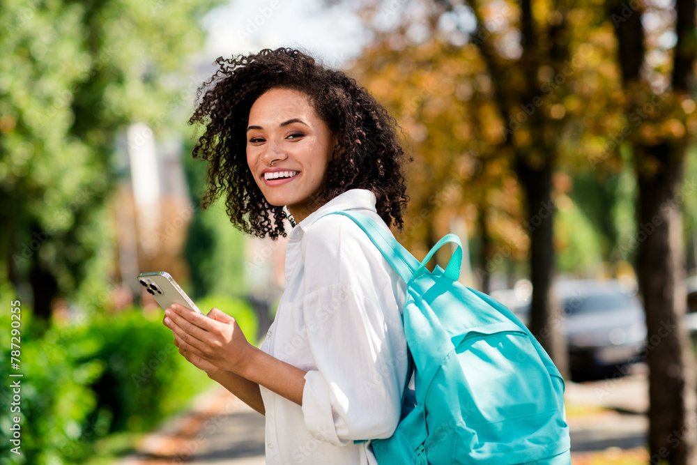 Sticker Photo of pretty cheerful lady wear white shirt rucksack walking college chatting modern device outside urban city park