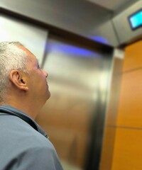Man in profile, inside the elevator while checking its operation. Technician at work. Faulty...