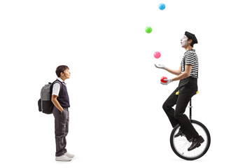 Full length shot of a schoolboy looking at a mime juggling with balls and riding a unicycle © Ljupco Smokovski
