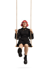 Young woman with red hair wearing a black dress and sitting on a swing