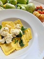 plate with egg ravioli pasta, ravioli with crumbled mozzarella, plate with Italian dish, sliced basil