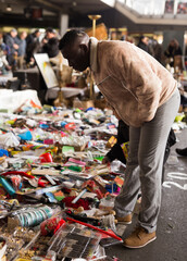 Ordinary african american guy chooses hands clothes at flea market