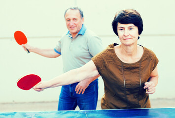 Mature man and woman playing table tennis