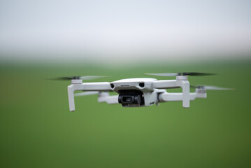 Drone hovering in the air, close up. Quadcopter on green summer background, modern equipment concept