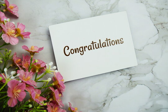 Congratulations text message on paper card with flower decoration on marble background