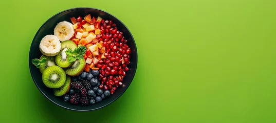 Foto op Plexiglas Vibrant tropical fruit salad bowl on green background with papaya, pomegranate, and banana © Ilja