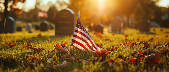 An American flag stands out in the warm sunset light at a peaceful veterans cemetery adorned with autumn leaves.
