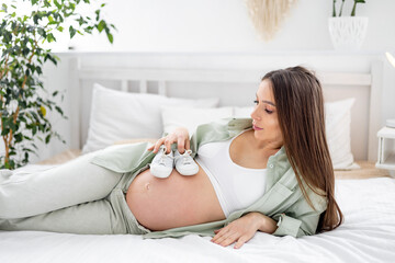 A pregnant woman with a big open belly holds socks and dreams of having a baby. The expectant...
