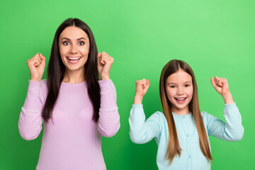 Portrait of two people mother daughter raise fists shout yes isolated on bright green color background - obrazy, fototapety, plakaty