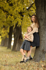Family day. Young mom and little daughter having fun and enjoy relaxing outdoors in autumn park. Adorable child girl tightly hugs and kiss her mother. Maternal care and love for kid. Mothers day