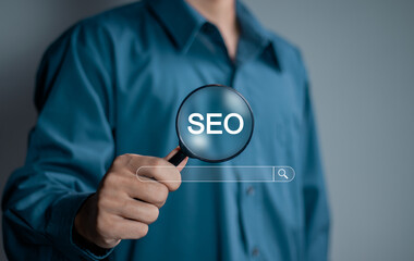 Businessman using magnifying glass focus to SEO icon to analyze SEO search engine optimization for...