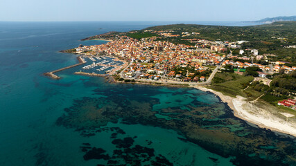Fototapeta premium Aerial view of Portoscuso, an Italian municipality in the province of Southern Sardinia, Italy. The town, built on the sea, also has a small port that is very active in the summer season.