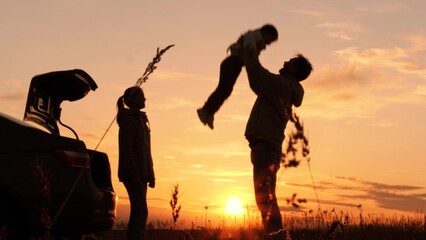 Silhouette of father tossing child in air. Family traveling by car having fun in nature laughing smiling enjoying life. Happy moments together. Loving dad with daughter and wife at weekend travel trip - obrazy, fototapety, plakaty