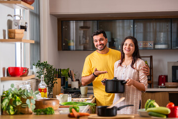 Indian couple in kitchen - Young Beautiful asian couple preparing food in home kitchen.