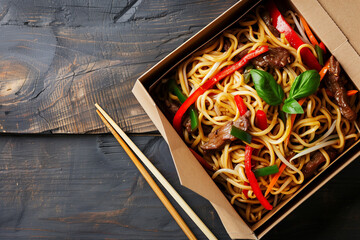 Close-up of noodles in a box with vegetables and beef, traditional chinese street food in a carton with chopsticks with space for text or inscriptions, top view