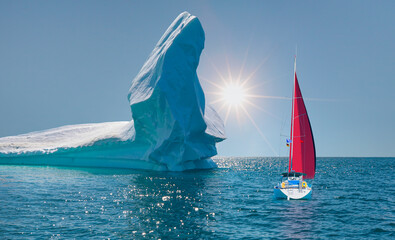 Giant iceberg near Kulusuk with lone yacht with red sails - Greenland, East Greenland