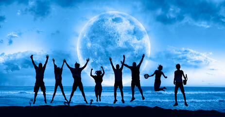 A group of young people jumping under the moonlight by the sea  "Elements of this image furnished by NASA"