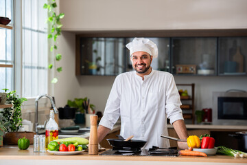 confident asian indian male young chef portrait in kitchen