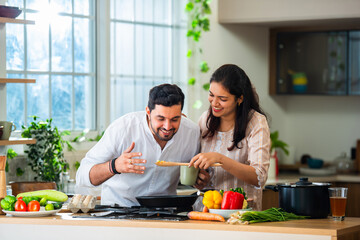 Indian couple in kitchen - Young Beautiful asian wife enjoying cooking with husband.