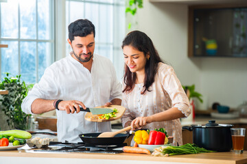 Indian couple in kitchen - Young Beautiful asian wife enjoying cooking with husband.