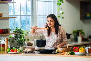Asian Indian young female housewife preparing food in the kitchen