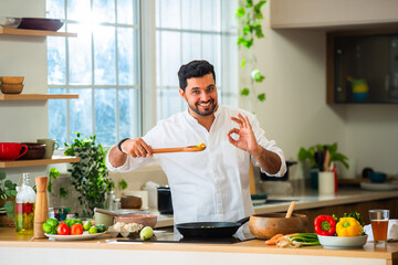 Naklejka premium Indian man preparing breakfast in modern kitchen