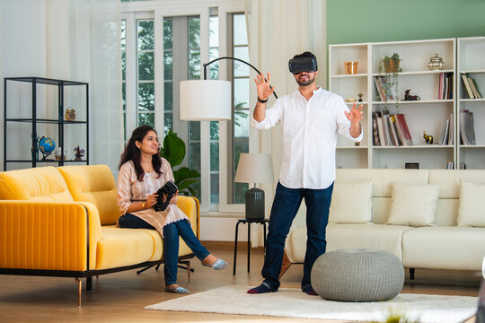 Indian asian young couple wears VR eye glasses and playing games at home.