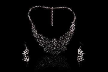 Openwork silver set of necklace and earrings isolated on a black background.