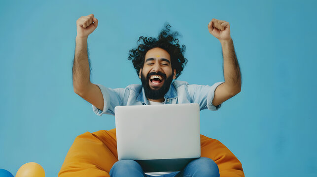 Happy curly bearded millennial hindu guy in casual gambling online sitting at bean bag over blue studio background using brand new laptop raising hands up celebrating success copy spac : Generative AI