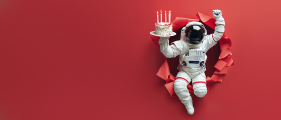 This image captures a playful astronaut holding a birthday cake amid paper confetti, bursting through a red backdrop