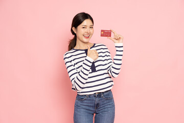 Young beautiful Asia woman smiling, showing, presenting credit card for making payment or paying online business isolated on pink background - 787348210
