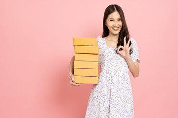 Young Asian woman holding package parcel box isolated on pink background, Delivery courier and shipping service concept - 787348632