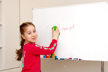 cute little girl erases the inscription i love you from the board