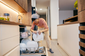 A japanese middle-aged housewife is doing dishes at home.